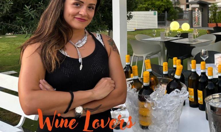 Donna sorridente con vini in giardino.