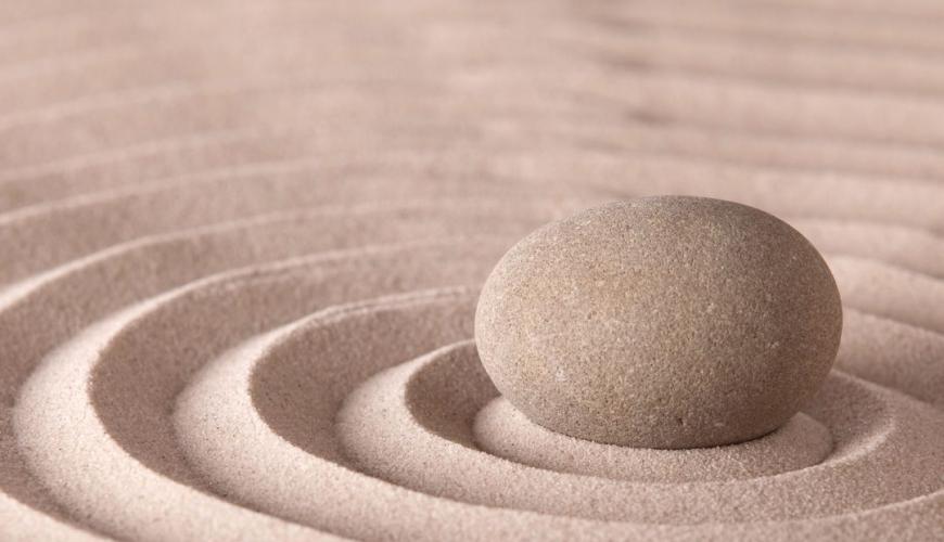 Pietra su sabbia con cerchi concentrici, simbolo di serenità.