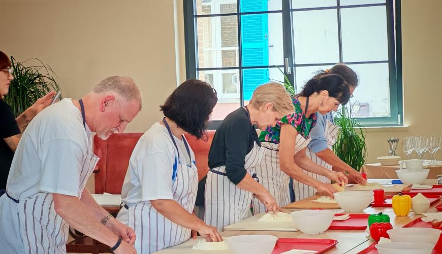Gruppo di persone felici cucina insieme in una luminosa aula di cucina.