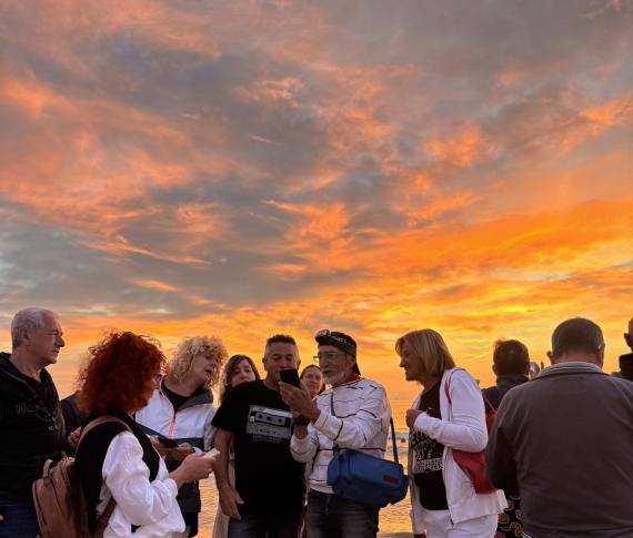 Gruppo di persone sulla spiaggia al tramonto.