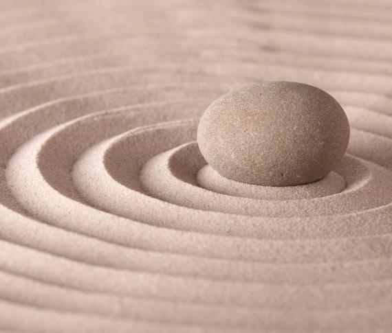 Pietra su sabbia con cerchi concentrici, stile giardino zen.