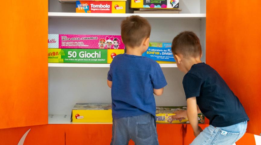 Kinder wählen Spiele von einem bunten Regal aus.
