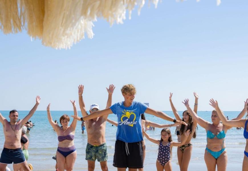 Persone fanno esercizi sulla spiaggia con un istruttore.